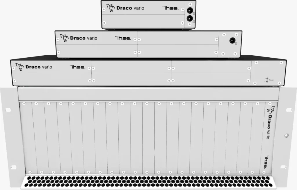 The image features a Draco Vario chassis comprising three extender modules of varying sizes. Positioned in a pyramid formation, the base module is large, the middle one is medium-sized, and the top one is small. All three modules are situated atop a larger aluminum silver box.