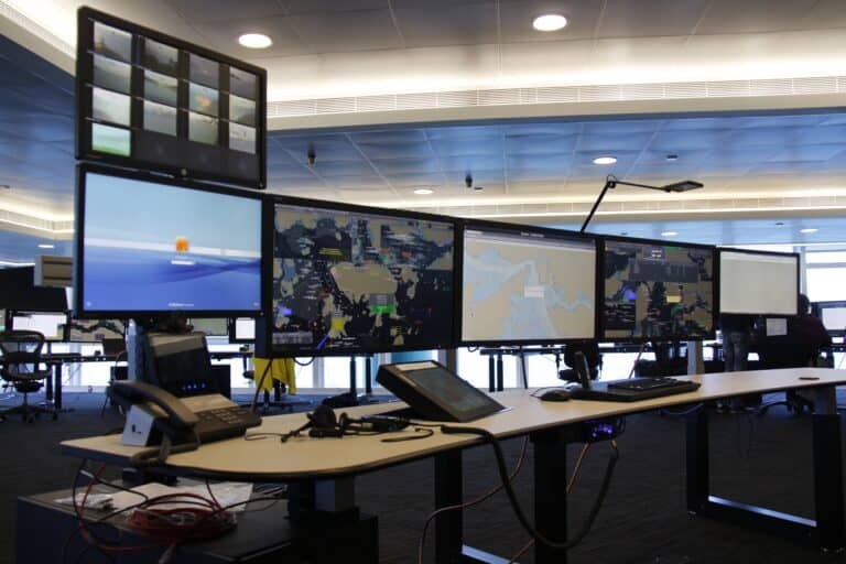 Control room with multiple screens and operators managing oil platform operations.
