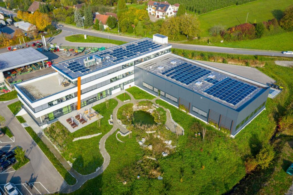 IHSE headquarters surrounded by a garden featuring a unique biotope with two natural ponds, native plants, animal habitats, insect hotels for wild bees, and honeybee hives. Awarded an environmental certificate by TÜV SÜD - IHSE.